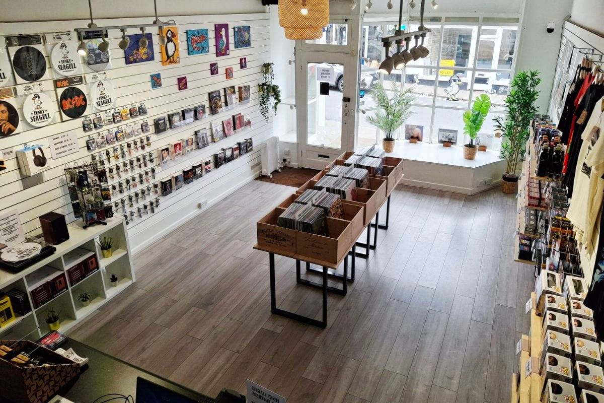 Funky Seagull store interior with record players, books, artwork, and keyrings on display with plants on a wooden floor.
